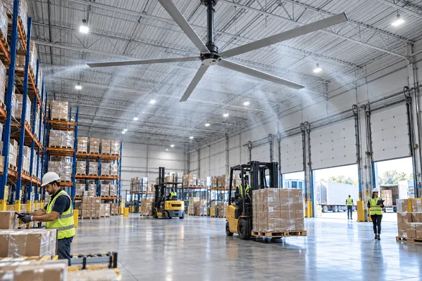 High volume low speed fans circulating air over workers and material-handling zones in a warehouse